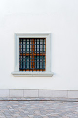 Urban background. White wall with small window and iron grate