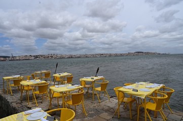 yellow tables of a restaurant on an old pier on the Tago river in Lisbon, Portugal