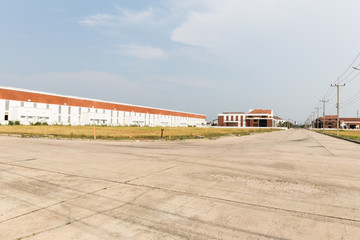 Fototapeta na wymiar empty road with green field in the back of warehouse buildings