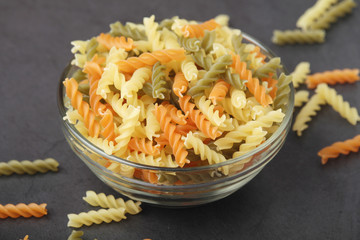 A bowl with uncooked pasta fusilli tricolore	