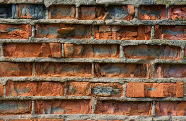 Cracked vintage orange bricks in the wall with cement masonry close-up