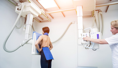 Radiologist and patient in a x-ray room. Classic ceiling-mounted x-ray system.