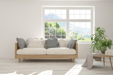 Stylish room in white color with sofa and summer landscape in window. Scandinavian interior design. 3D illustration