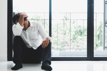 Young asian man sitting in the dark room hand in head feeling depressed, lonely, dramatic and sad.