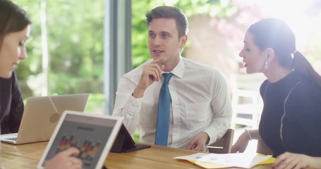 4K Happy young business team looking at sales figures on computer & discussing. Slow motion.