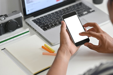 Cropped shot hands using mockup mobile phone on office desk.