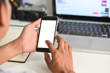 Cropped shot hands using mockup mobile phone on office desk.