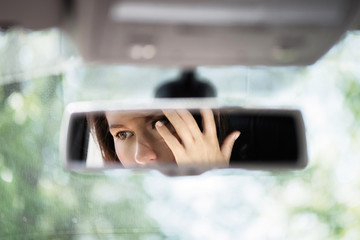 Reflection of a beautiful young woman face in the car rear view mirror. concept