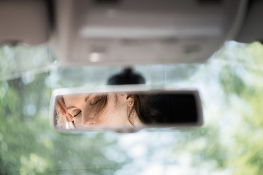 Reflection Of A Beautiful Young Woman Relaxing With  Closed Eyes In The Car Rear View Mirror. Concept.