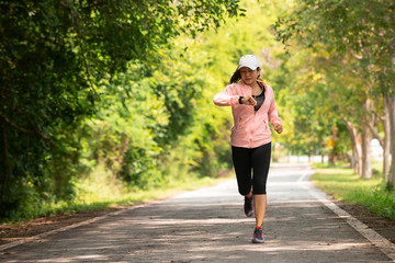 Asia woman runner running while checking heart rate  at park, female in sport cloth jogging while...
