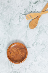 Flat lay top view of wooden spoons, wooden disk pattern on marble table.