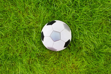 Obraz premium A football ball on green grass. A view from above.