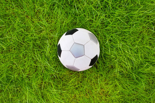 A football ball on green grass. A view from above.