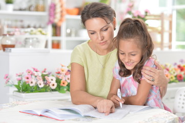Cute little girl with her mother doing homework together