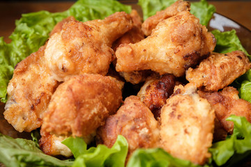 Fried chicken shins in a crispy crust on lettuce leaves in a plate.