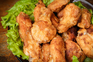 Fried chicken shins in a crispy crust on lettuce leaves in a plate.