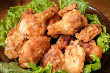 Fried chicken shins in a crispy crust on lettuce leaves in a plate.