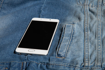 white phone in the pocket of a denim jacket