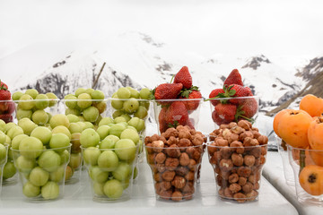 Pieces of fresh fruit in glasses on background of Caucasus Mountains among the snows, Georgia