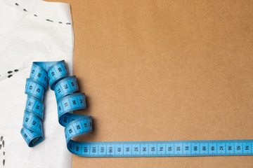 close-up tailor measuring tape on tracing paper pattern on craft paper background. Blue measuring tape shallow depth of field.