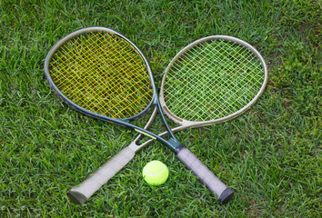 Wimbledon sign, two tennis rackets with a ball on grass