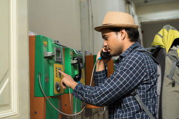 Fototapeta premium Young traveler using public payphone