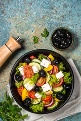 Greek salad in black plate on the table.