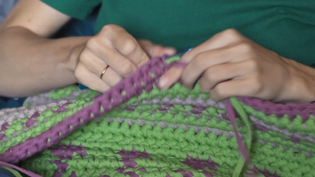 Young woman knitting warm sweater indoors