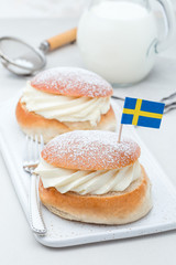 Traditional swedish dessert Semla, also called Shrove bun, with almond paste and whipped cream filling, served with a milk, vertical