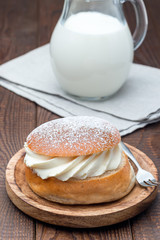 Traditional swedish dessert Semla, also called Shrove bun, with almond paste and whipped cream filling, served with  milk, vertical