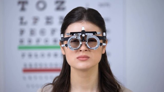 Doctor choosing lenses for patient in optical trial frame, lady shaking head