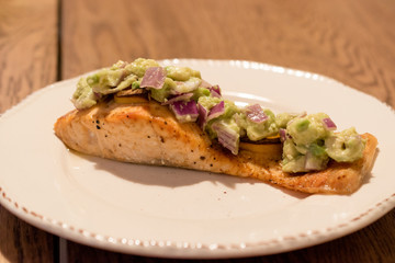Salmon Fillet with Avocado in Plate at Dinner Table.