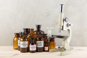 Vintage pharmaceutical bottles, microscope and stethoscope on the wooden desk - retro pharmacy