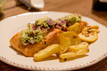 Salmon Fillet with Avocado in Plate at Dinner Table.