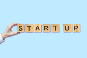Concept Start. Female hand holds an inscription on wooden blocks on a blue background. Isolated. Concept technology launch project. Business.