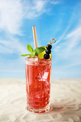 Fresh cold cocktail with ice and fruits by beach