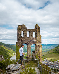 men sitting on rock looking out over moselle river Germany, ,Grevenburg castle,At the ruins of...