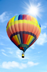 Colorful hot air balloon over bright sky with clouds.