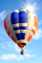 Fototapeta premium Colorful hot air balloon over bright sky with clouds.