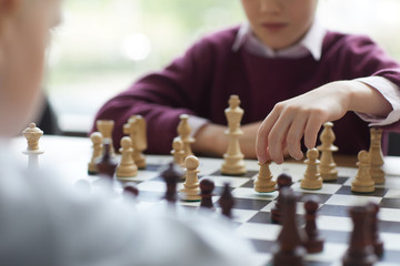 Girl in purple sweater playing chess, making move and putting indecisively chess piece on board