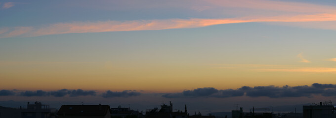 Sunset panorma with cityscape in dark shadow, blue orange soft colors