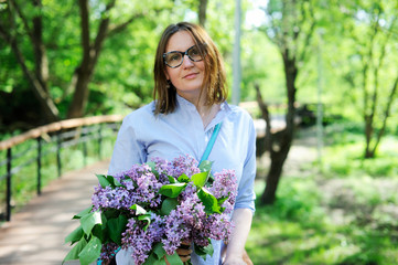 Beautiful young woman with bouquet of lilac