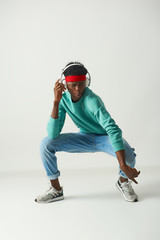 Smiling young man in casual clothes is making dance moves