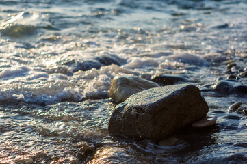 rocky sea shore with pebble beach, waves with foam