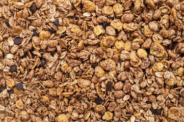 Muesli with oatmeal cereals and chocolate as background. Fitness breakfast. Healthy food. Top view. Close up