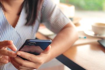 Woman typing text message on smart phone in a cafe.
