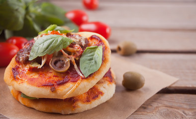 Homemade mini pizza on the wooden background.