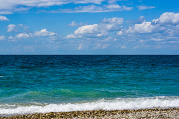 sea landscape is a pebbly beach with waves in white foam