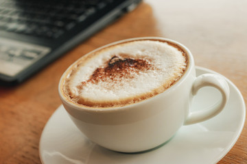 Freelancer working in cafe on a wooden counter bar with coffee mugs and laptop.