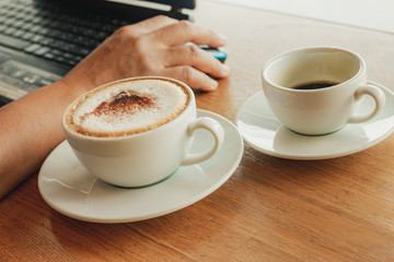 Freelancer working in cafe on a wooden counter bar with coffee mugs and laptop.